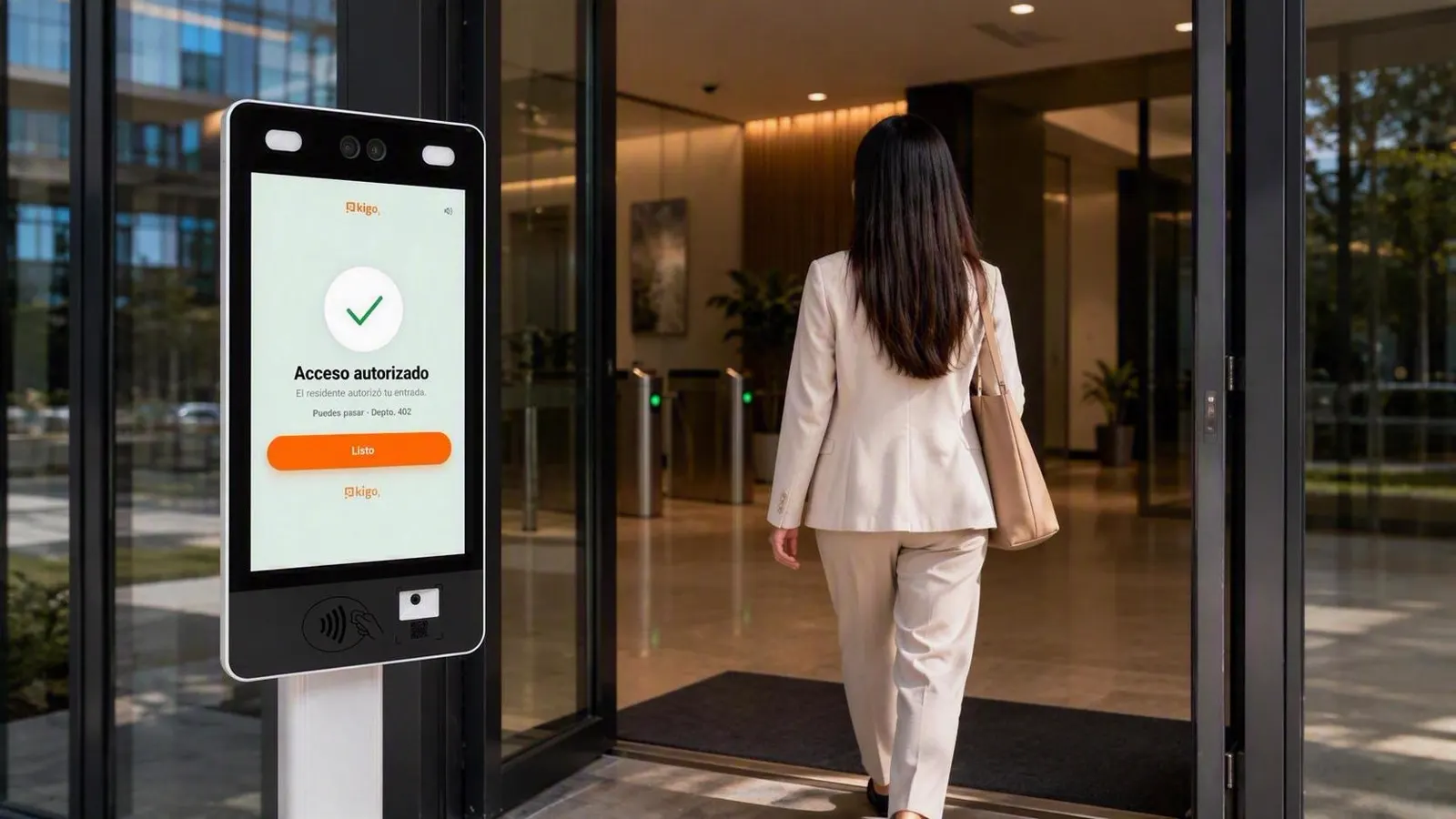 Visitante entrando al lobby tras el torniquete, con el terminal Kigo mostrando «Acceso autorizado» en la puerta
